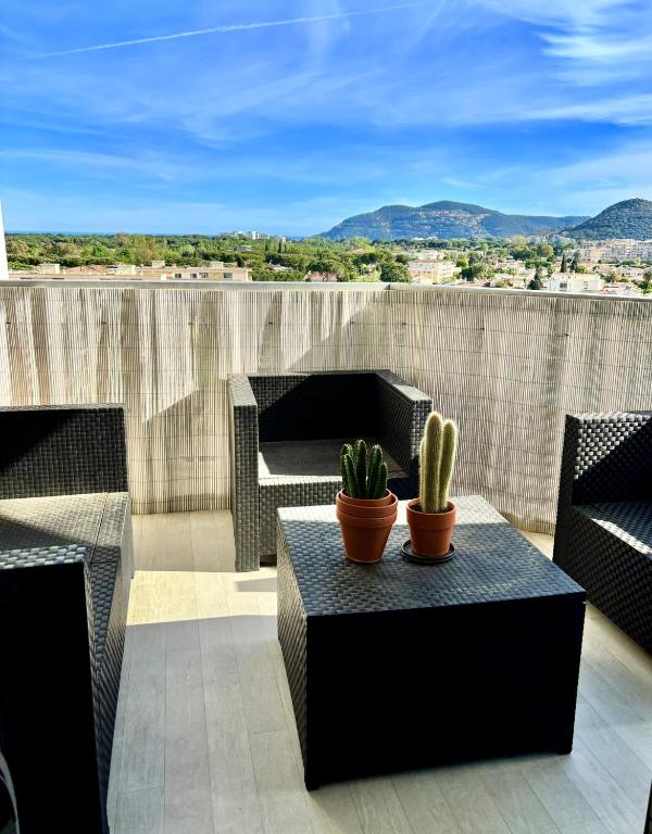 un patio avec une table et des cactus sur un toit dans l'établissement T1 panoramique, à Mandelieu-la-Napoule