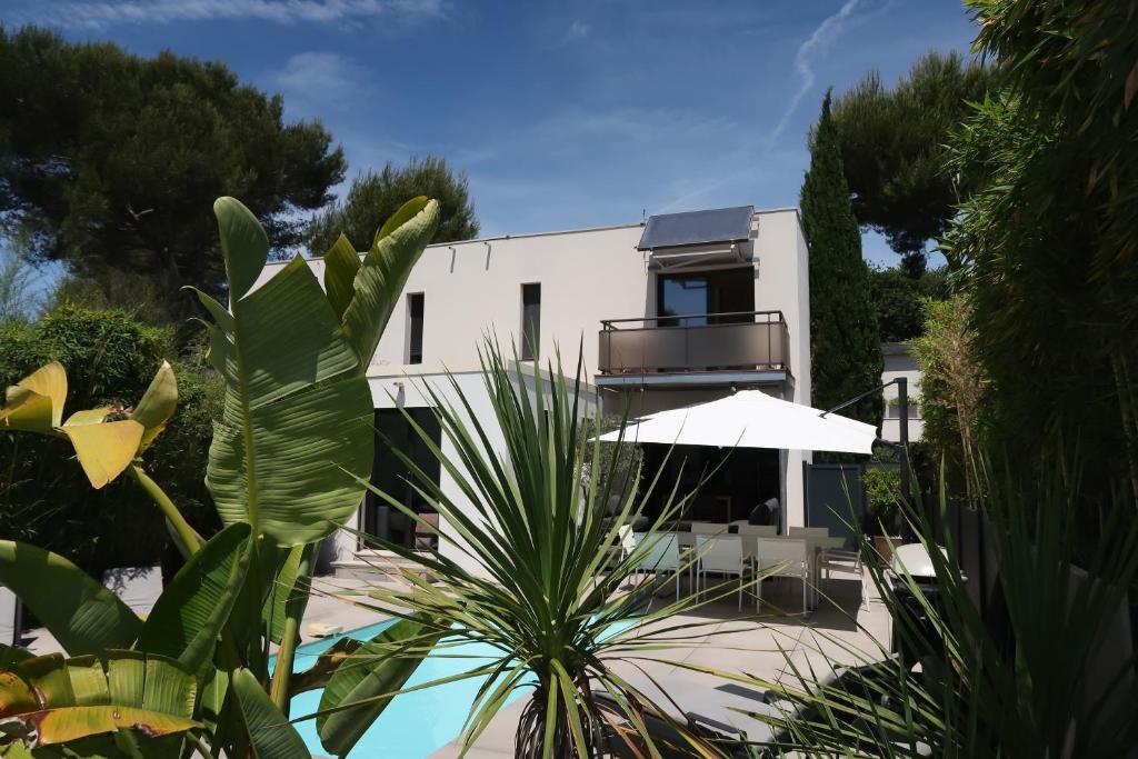 - un bâtiment blanc avec une terrasse et un parasol dans l'établissement Magnifique Villa californienne avec piscine privative, à Antibes