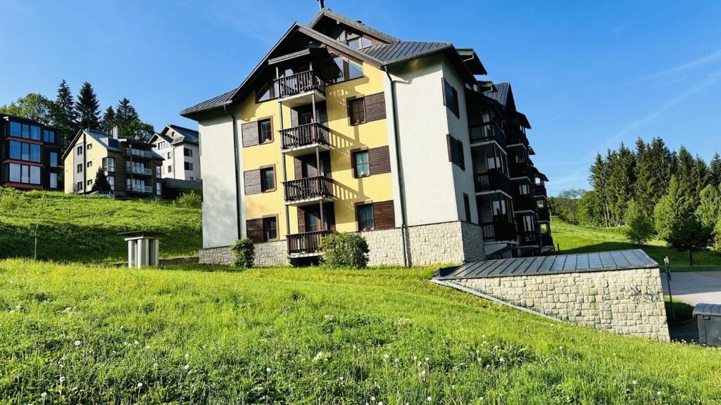 a large yellow and white building on a hill at Apartmán Špindl 101čka Dalibor II in Špindlerův Mlýn