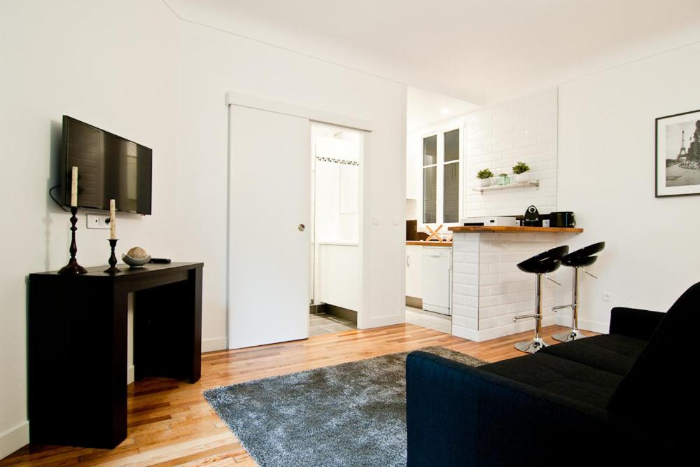 un salon avec un canapé noir et une cuisine dans l'établissement Elégant appartement Proche Champs Elysées, à Paris