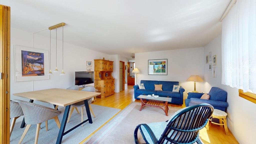a living room with a blue couch and a table at Flurina 43 in Silvaplana