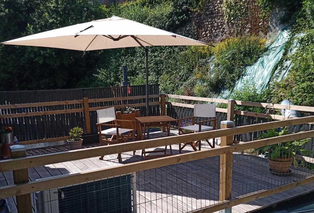 une terrasse en bois avec une table et un parasol dans l'établissement Quietude, à Honfleur