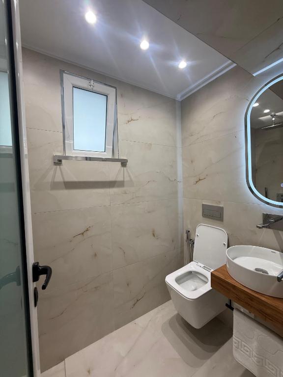 a bathroom with a toilet and a sink and a window at Hotel Barjami in Sarandë