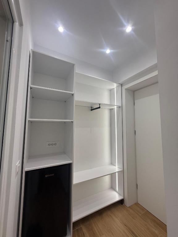 a closet with white shelves and a black refrigerator at Hotel Barjami in Sarandë