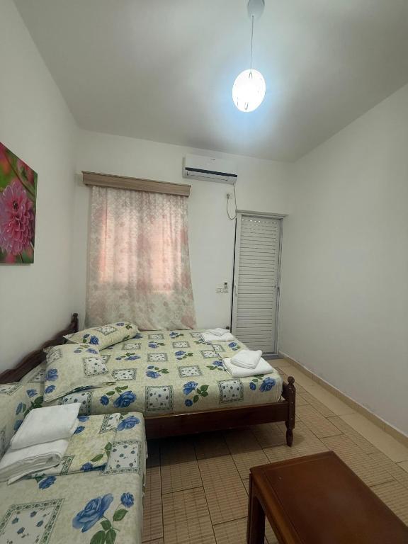 a bedroom with two beds and a table and a window at Hotel Barjami in Sarandë