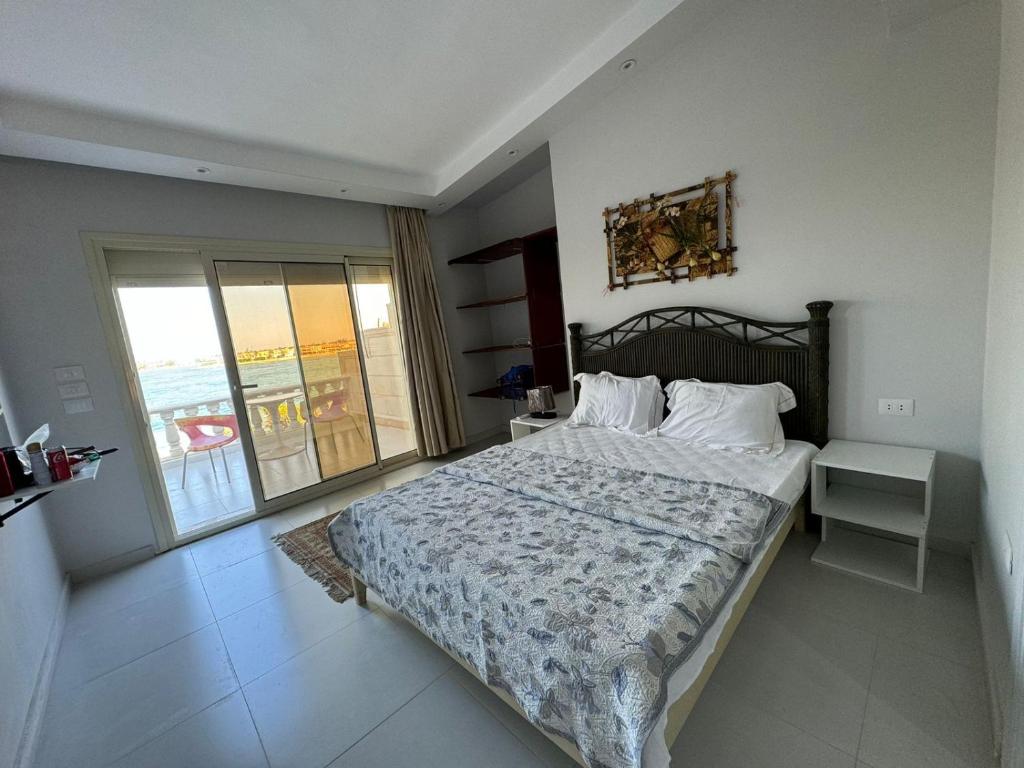 a bedroom with a large bed and a balcony at فيلا فاخرة بشاطئ خاص وإطلالة ساحرة على البحيرة in El Alamein