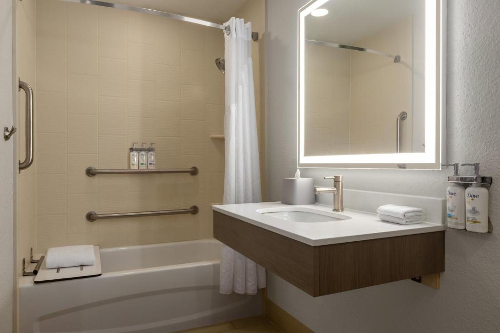 a bathroom with a sink and a tub and a mirror at Holiday Inn Express Fort Lauderdale Airport South by IHG in Dania Beach