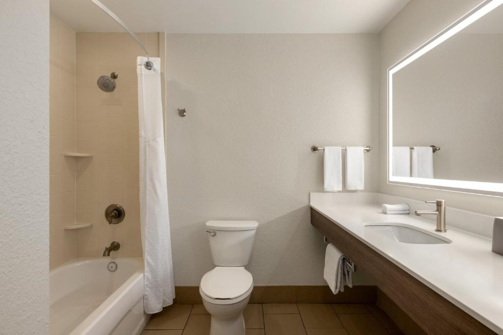a bathroom with a toilet and a sink and a tub at Holiday Inn Express Fort Lauderdale Airport South by IHG in Dania Beach