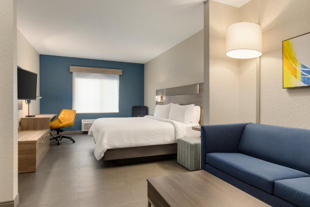 a hotel room with a bed and a couch at Holiday Inn Express Fort Lauderdale Airport South by IHG in Dania Beach