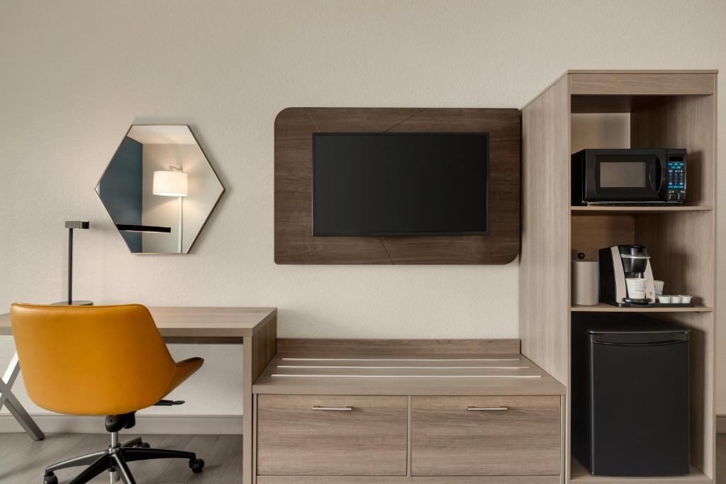 a room with a desk with a television and a chair at Holiday Inn Express Fort Lauderdale Airport South by IHG in Dania Beach