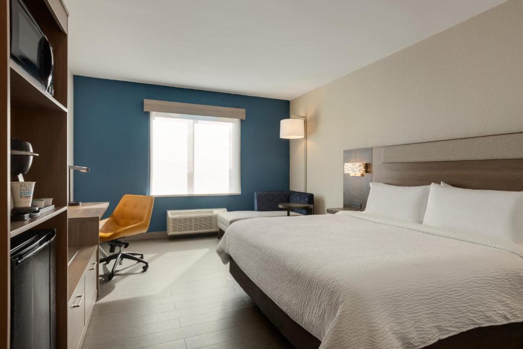 a hotel room with a large bed and a chair at Holiday Inn Express Fort Lauderdale Airport South by IHG in Dania Beach