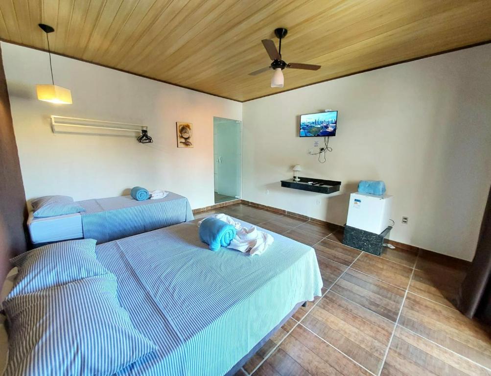 a bedroom with two beds and a tv on the wall at Conexão natureza in Socorro