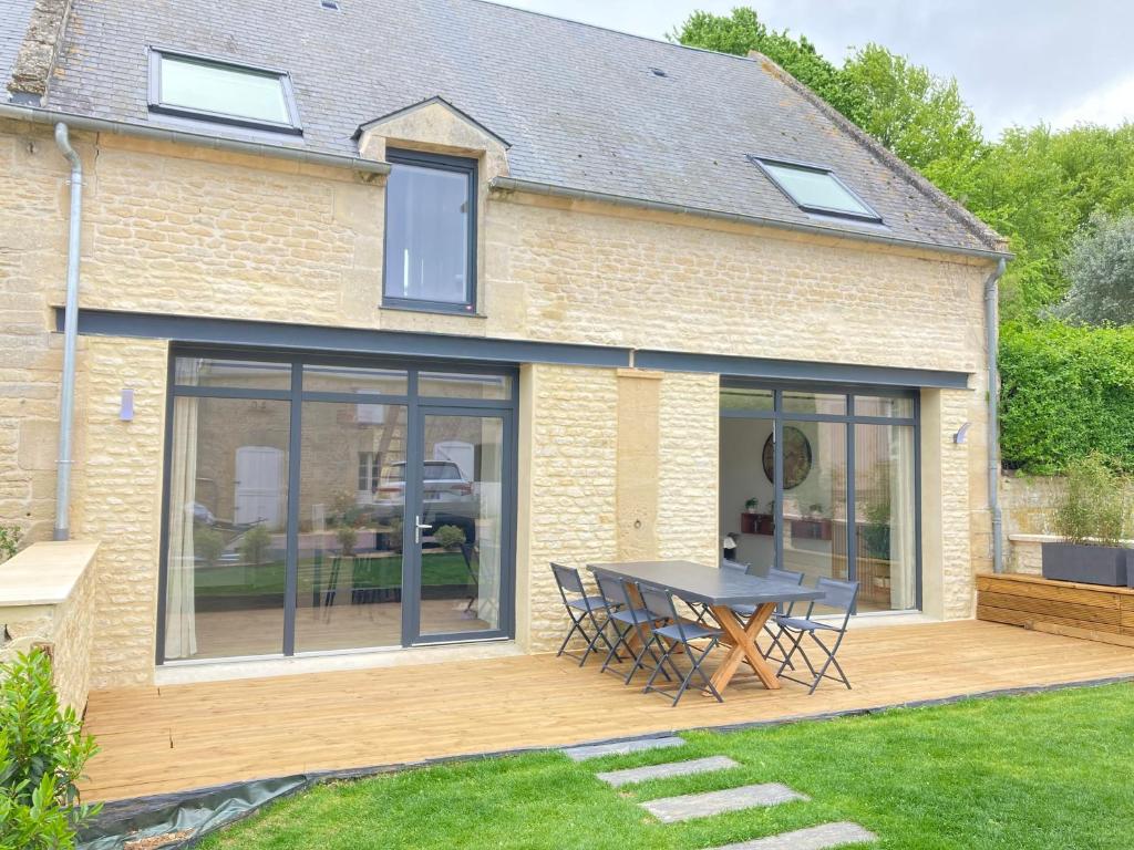 une maison avec un patio avec une table et des chaises dans l'établissement Entre Terre et Mer Meublé de tourisme 3 étoiles, à Colomby-sur-Thaon