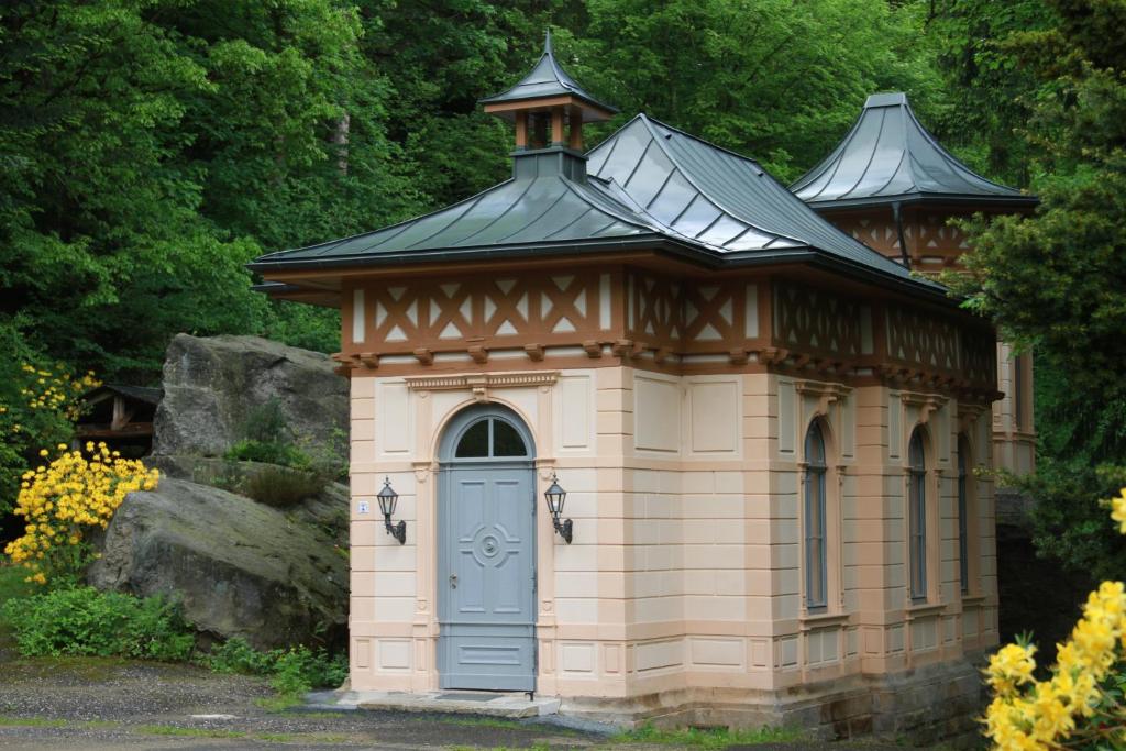 een klein gebouw met een blauwe deur in een tuin bij Ferienwohnung Jagdschloss Bielatal in Bielatal