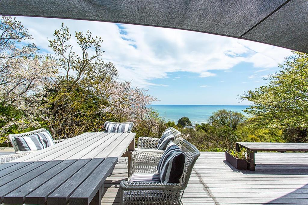 a wooden table and chairs on a deck with the ocean at VILLA PINECOVE - Vacation STAY 24656v in Kamogawa