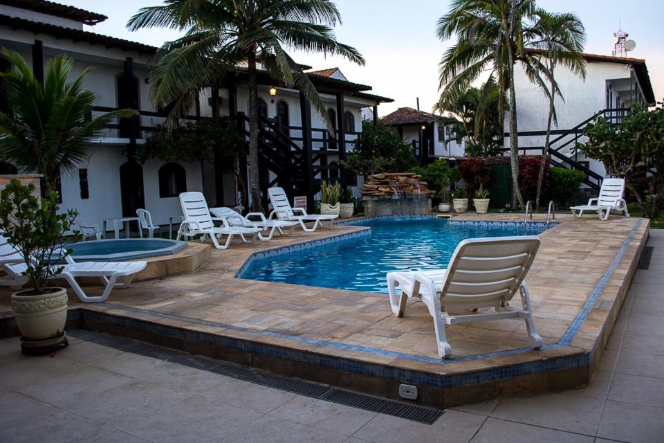 a swimming pool with lounge chairs and a swimming pool at Atlântico Hotel in Rio das Ostras