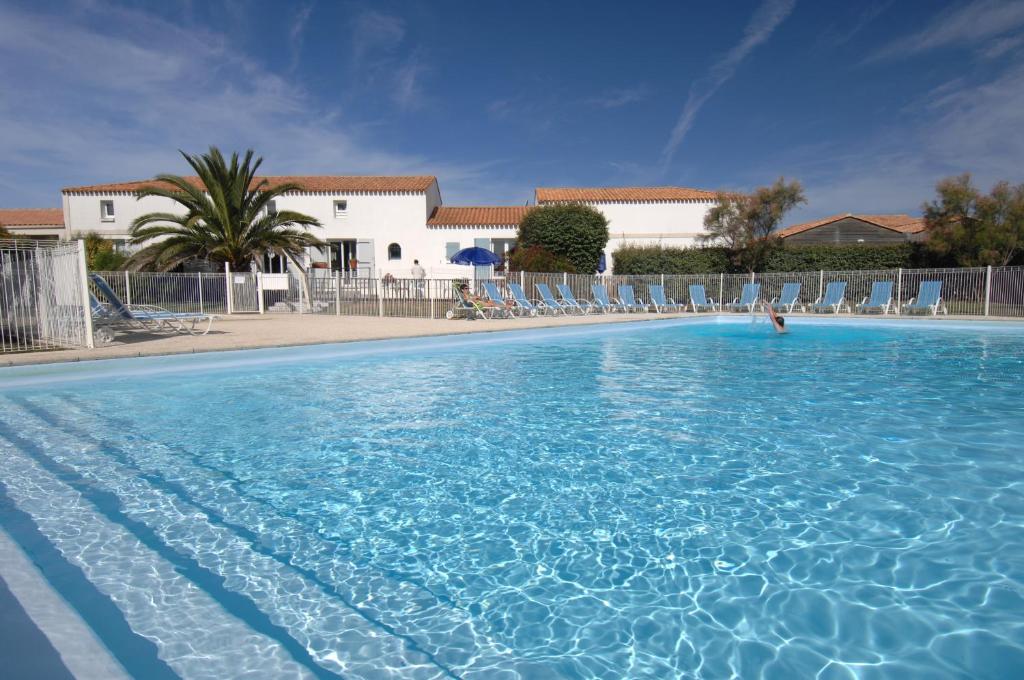 una gran piscina con sillas en un complejo en Résidence Odalys Le Village des Amareyeurs, en Le Château-dʼOléron