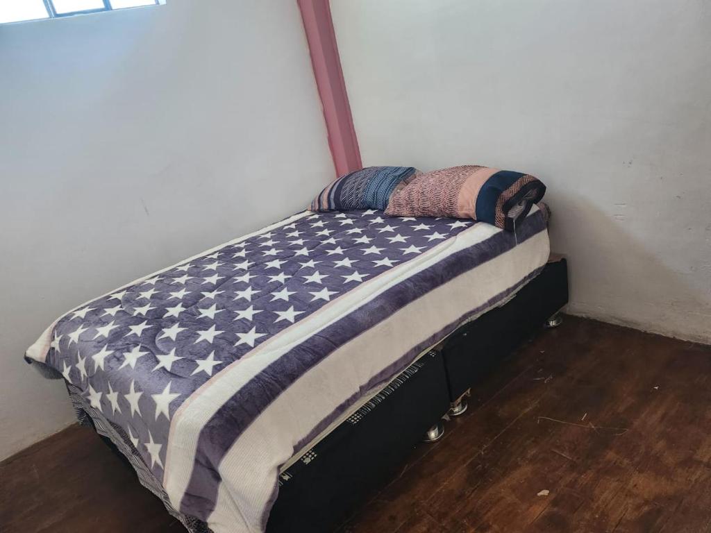 ein kleines Bett in einem Zimmer mit einer Decke mit amerikanischer Flagge in der Unterkunft Departamento Esmeralda in Chota