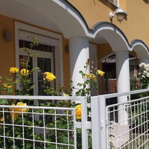 a white fence in front of a house with yellow flowers at Yellow Rose in Balatongyörök