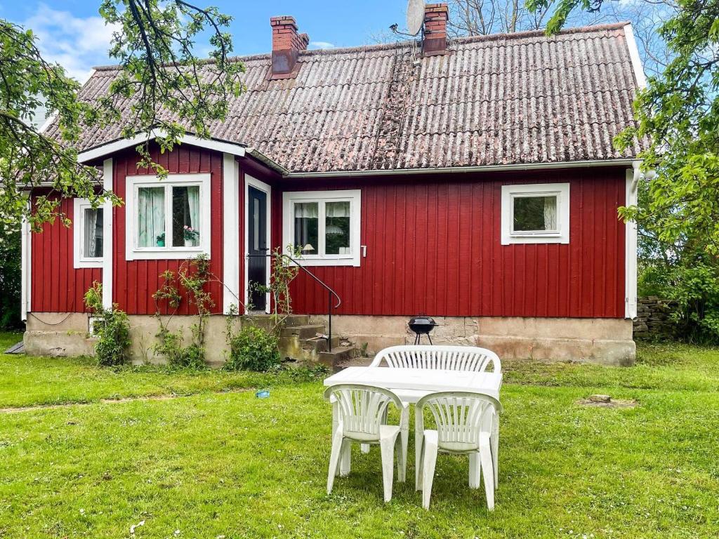 een rood huis met een tafel en stoelen ervoor bij 4 person holiday home in KÖPINGSVIK in Köpingsvik