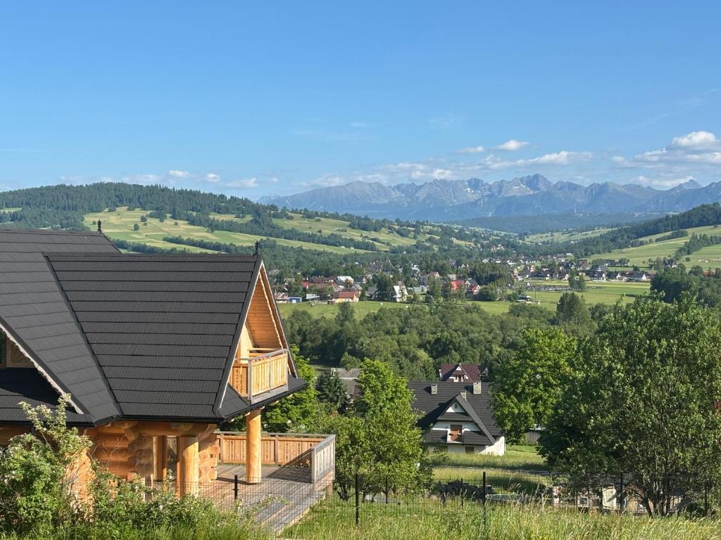a log cabin with a black roof and mountains in the background at Cicha Ostoja in Czarny Dunajec