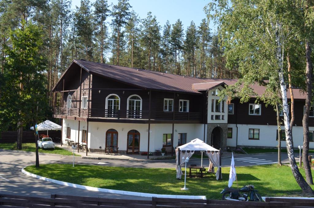 un grand bâtiment noir et blanc avec des arbres en arrière-plan dans l'établissement Motel Chalet, à Vita-Pochtovaya