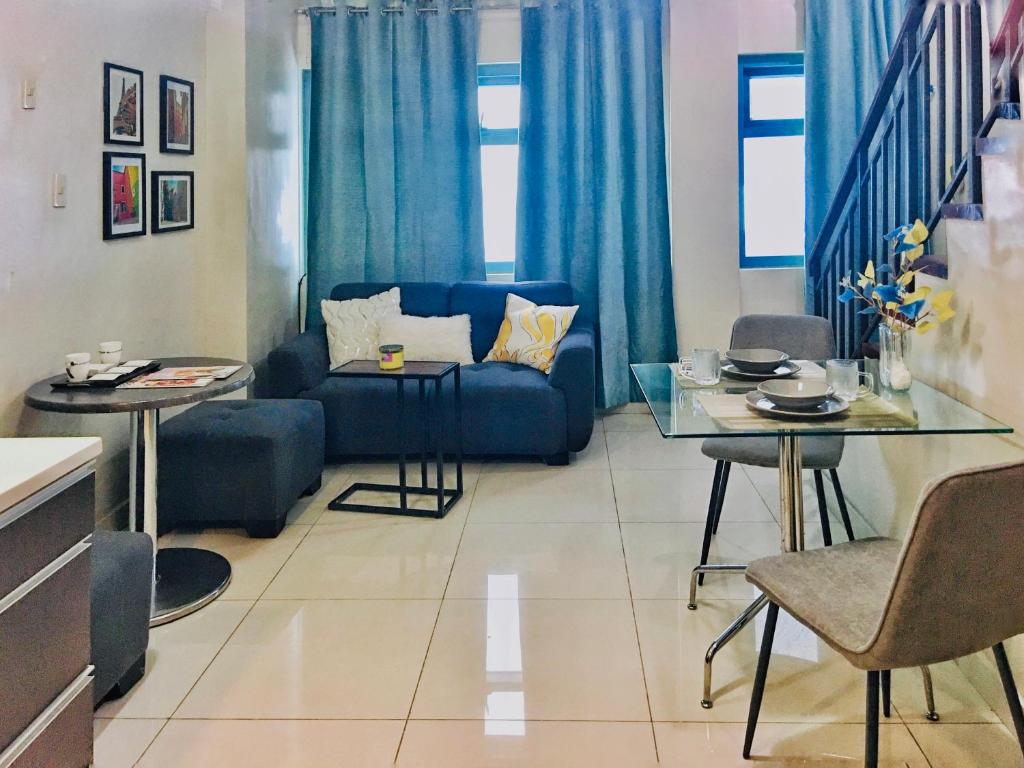 een woonkamer met een blauwe bank en een tafel bij One Bedroom Loft in the heart of Greenbelt Makati in Manilla