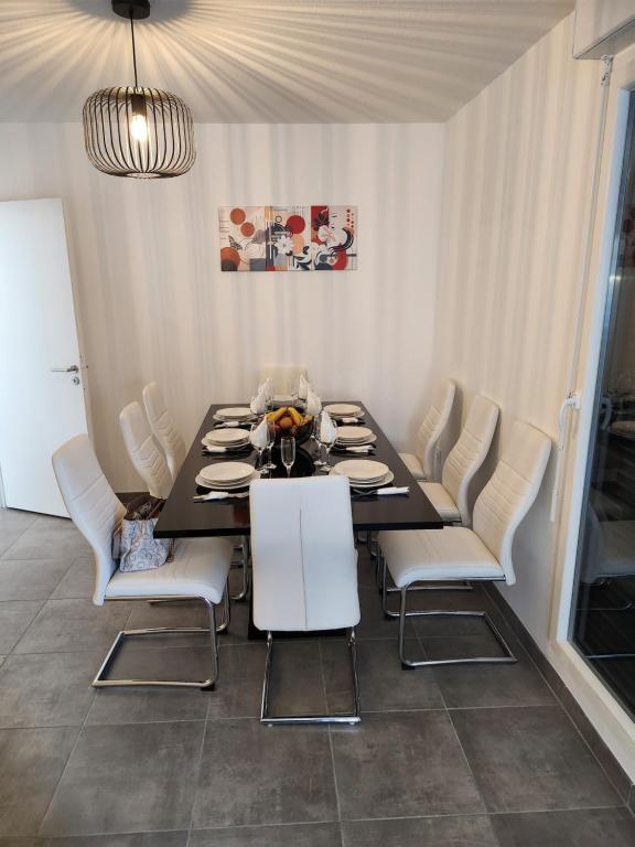 une salle à manger avec une table noire et des chaises blanches dans l'établissement Appartement Résidence Terra Cotta, à Toulouse