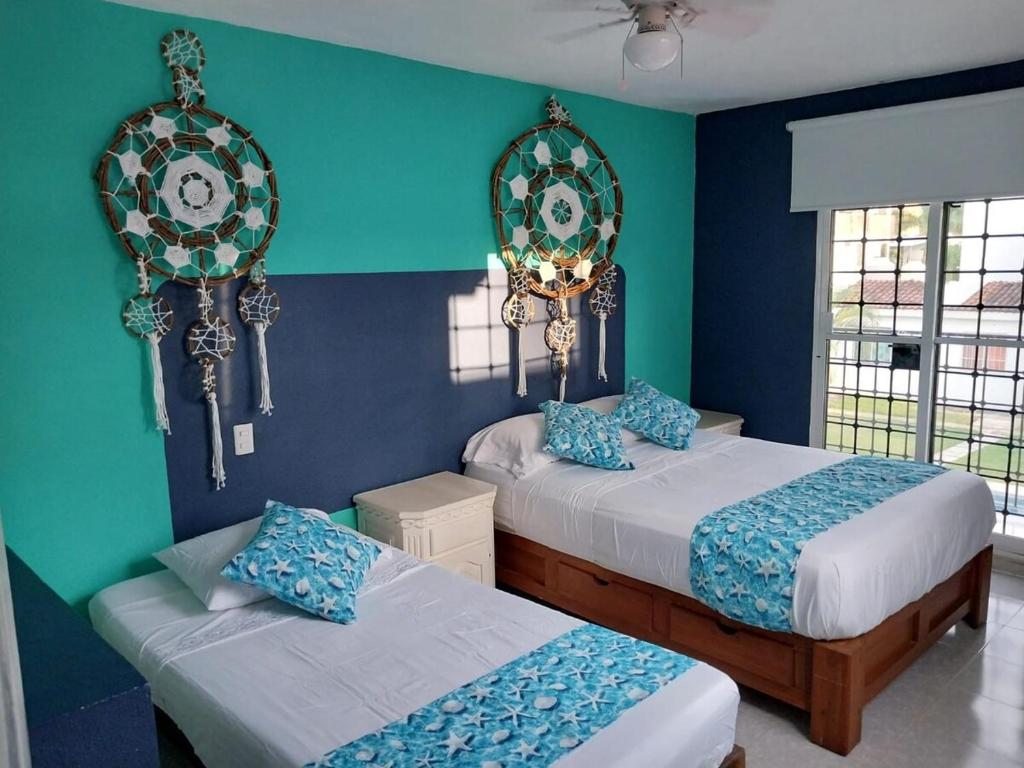 two beds in a room with blue and green walls at Casa de 4 habitaciones con alberca in Barrio Nuevo