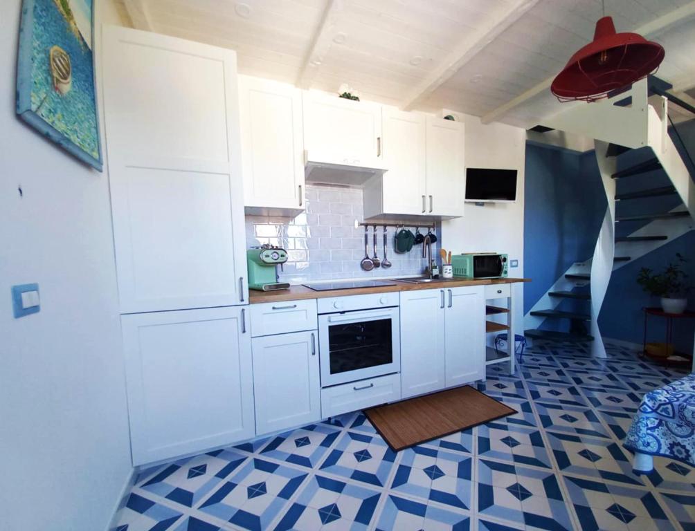 a kitchen with white cabinets and a blue and white tile floor at MinaMare Vacation Home in Torre Annunziata