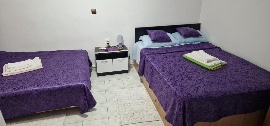 two beds in a room with purple sheets at Casa Dorului in Mangalia