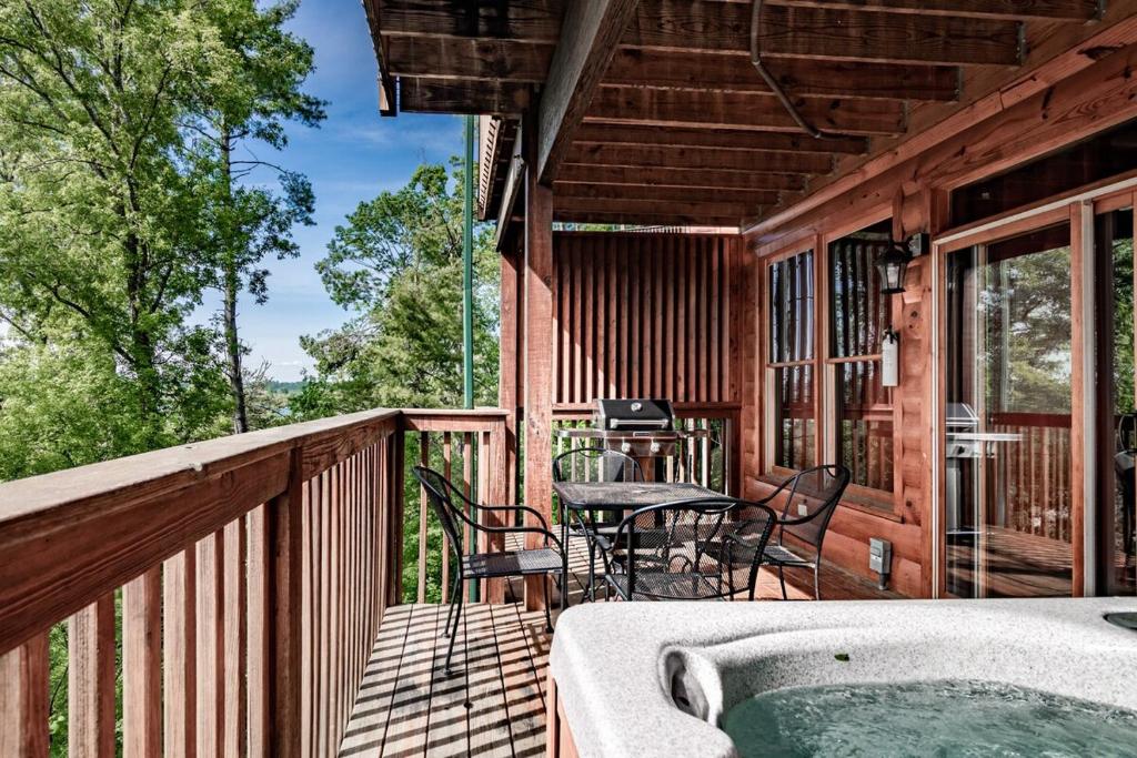 a porch with a hot tub and a table and chairs at Rustic Escape Cabin w Private Hot Tub & Grill in Pigeon Forge
