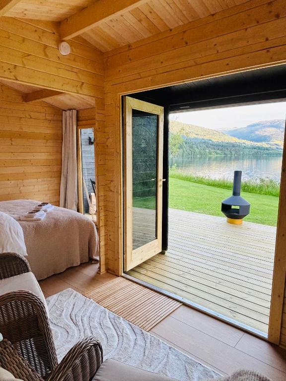 a room with a bed and a large sliding glass door at Simple Lakeside Anex - By the Water's Edge in Vossevangen