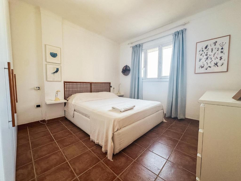 a bedroom with a bed and a window with blue curtains at Casa Bonita Vista Porto in Santa Teresa Gallura