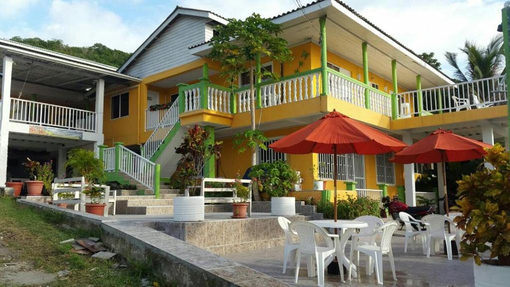 a yellow building with tables and umbrellas in front of it at Hotel Posada Enilda in Providencia