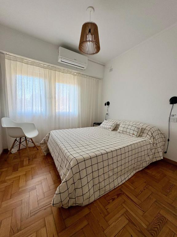 a bedroom with a bed and a chair and a window at Luminoso Depto al frente en el corazón del barrio Meridiano V- Meridiano Alquiler Temporario in La Plata