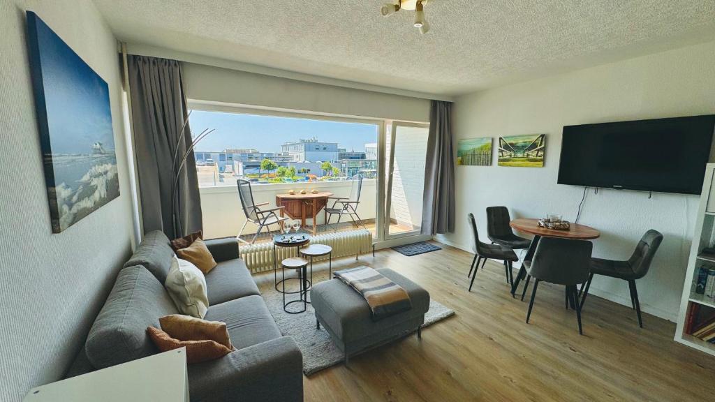 a living room with a couch and a large window at LUV & LEE Waterkant SPO in Sankt Peter-Ording