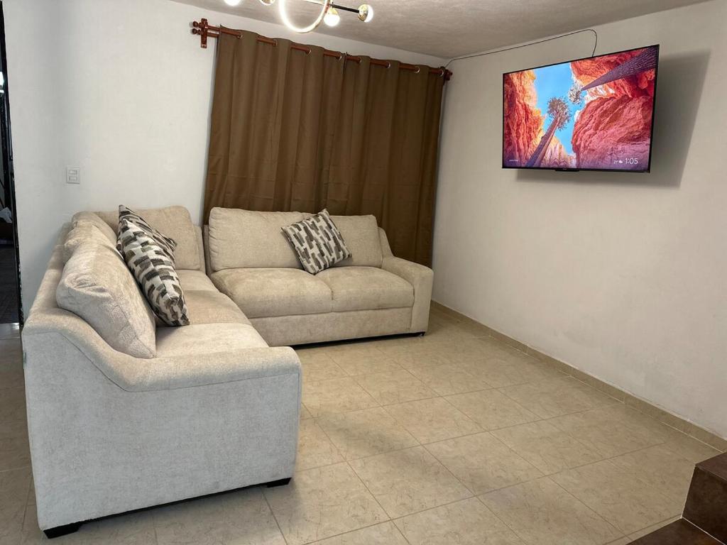 a living room with a couch and a tv on the wall at Casa Vista Al Sol in Zacatlán