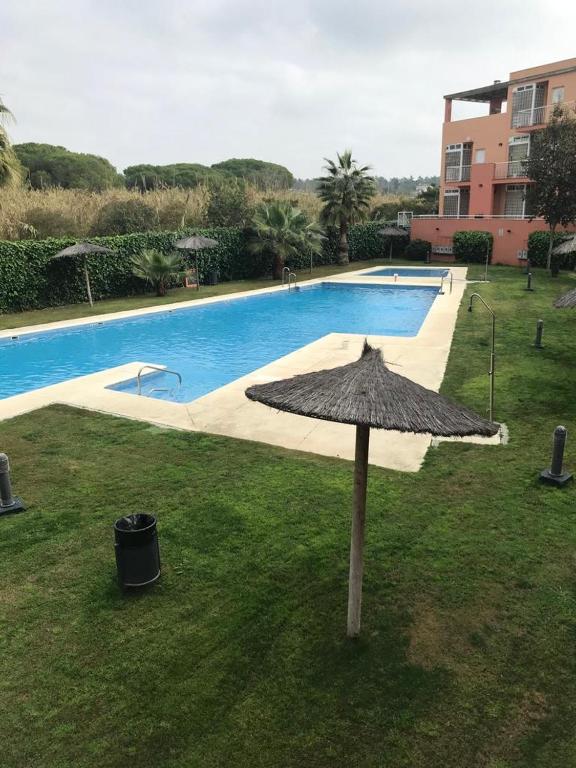 an umbrella in the grass next to a swimming pool at ISLANTILLA - URB GREEN 7 in Islantilla