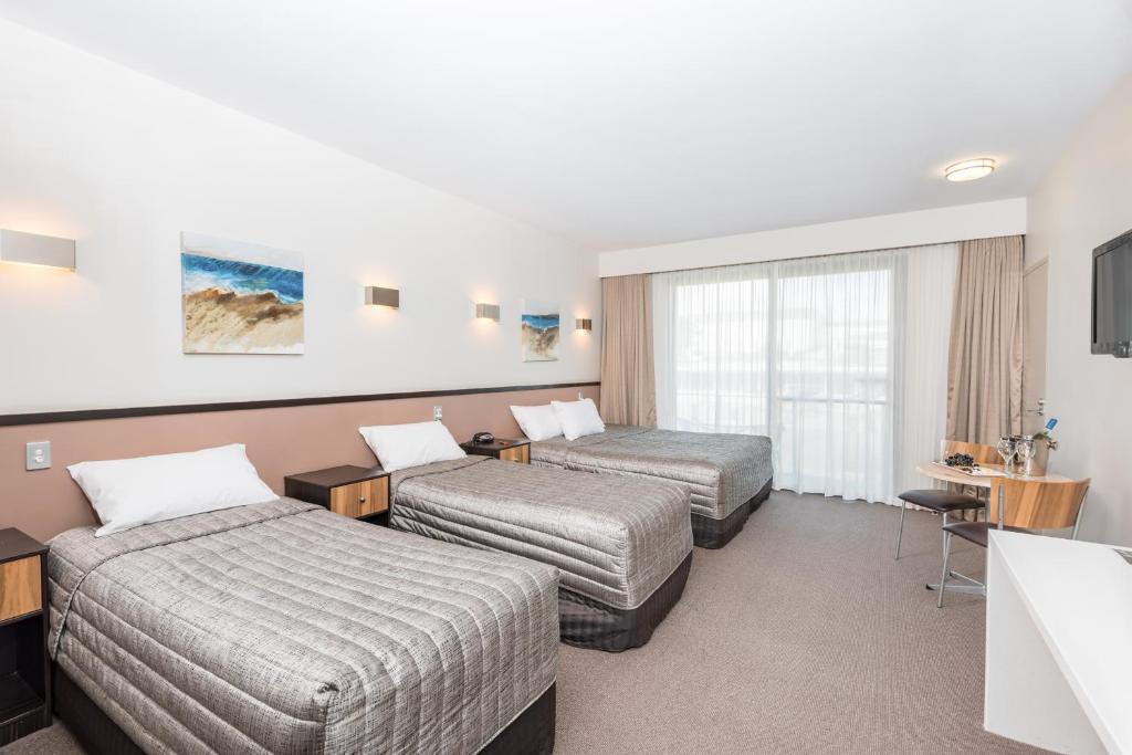 a hotel room with two beds and a television at Macquarie 4 Star in Warners Bay