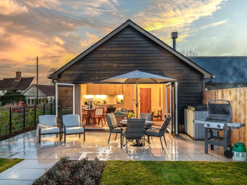 eine Terrasse mit Stühlen, einem Tisch und einem Sonnenschirm in der Unterkunft Uk47693 - Piglet Cottage in Wimbish