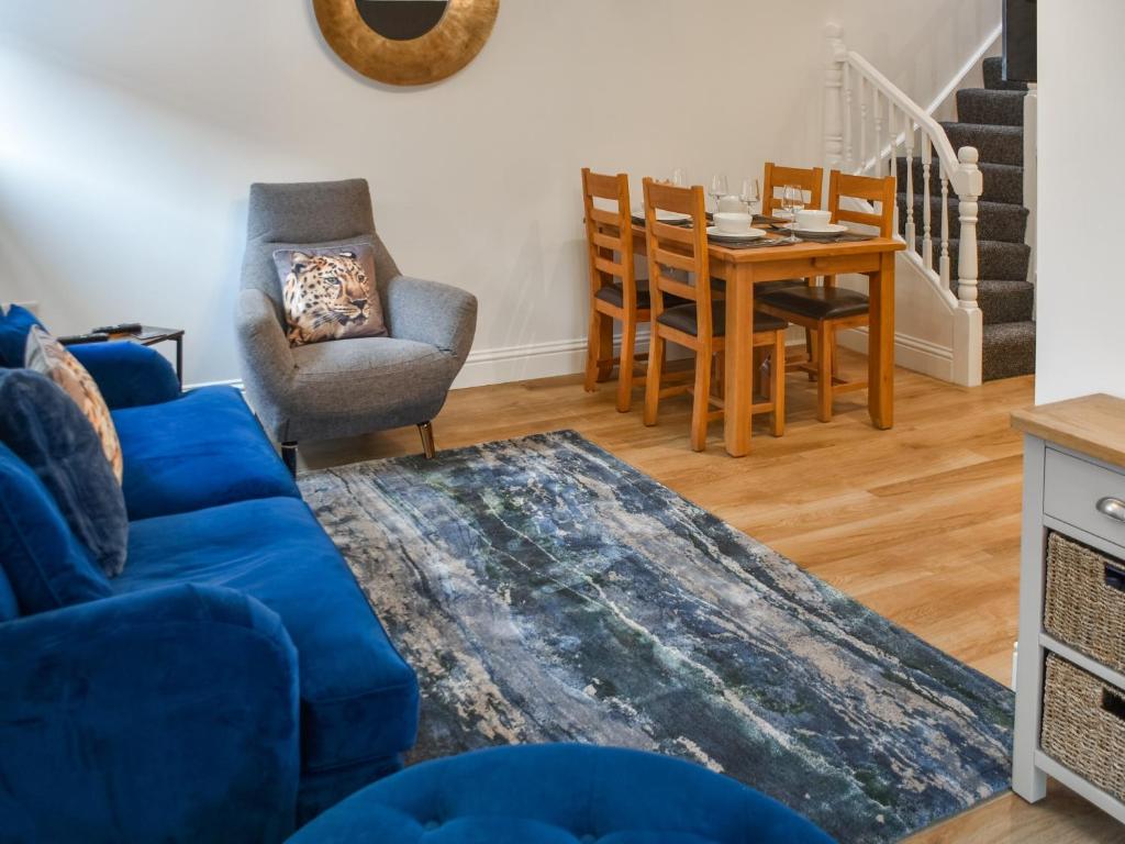 a living room with a blue couch and a table and chairs at Norfolk Headquarters in Fakenham