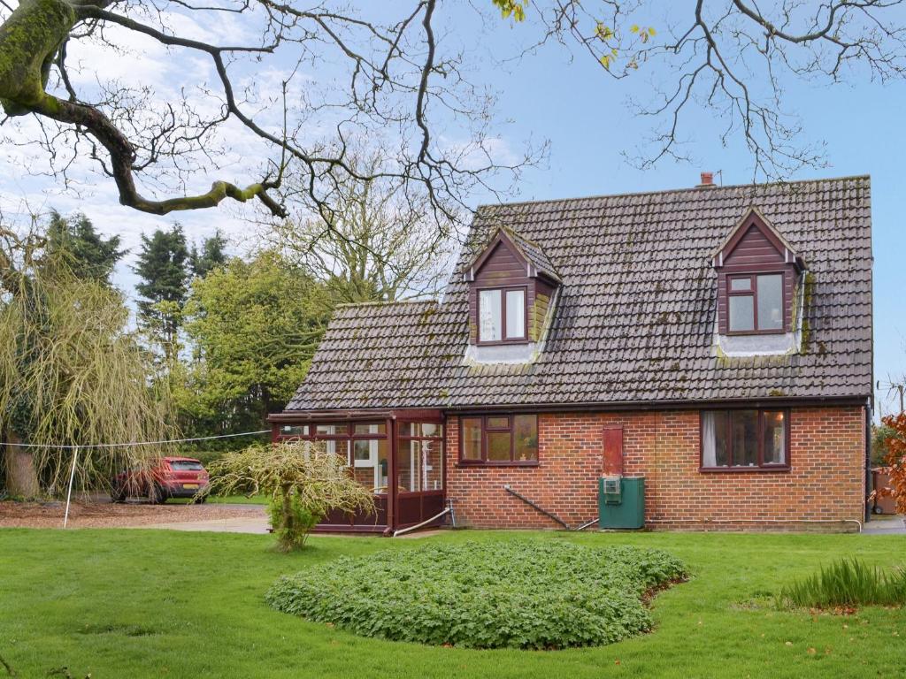 a red brick house with a green yard at Farmers Cottage in Withernsea