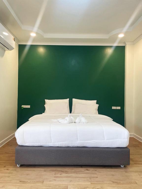 にあるNatcha Hotel and Residenceの緑の壁と大きなベッドのある寝室