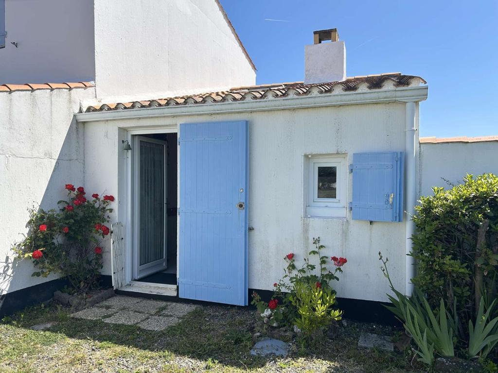 un petit bâtiment blanc avec des portes bleues et des fleurs dans l'établissement Maisonnette avec piscine chauffée, proche mer - FR-1-224A-78, à Bretignolles-sur-Mer