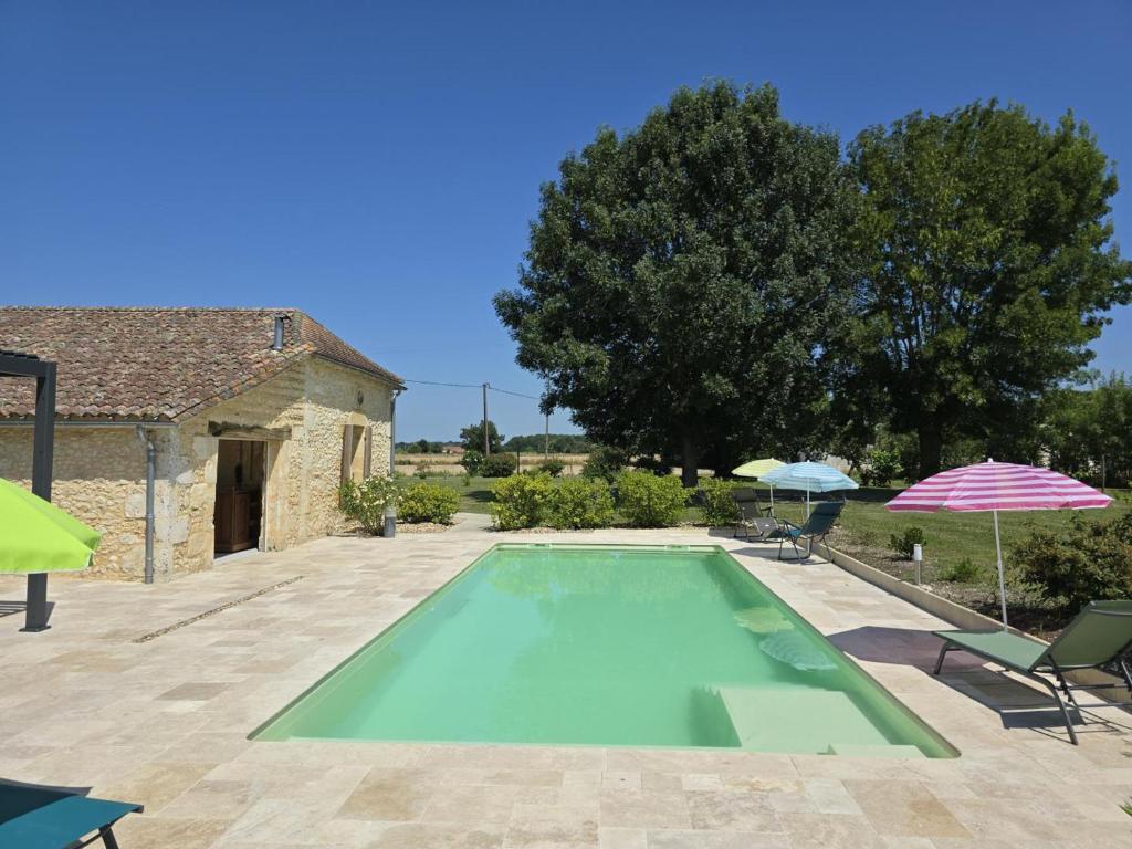 - une piscine en face d'une maison avec des parasols dans l'établissement Charmant Gîte en Périgord Pourpre avec Wifi et Terrasse Privée - FR-1-616-491, à Lamonzie-Saint-Martin