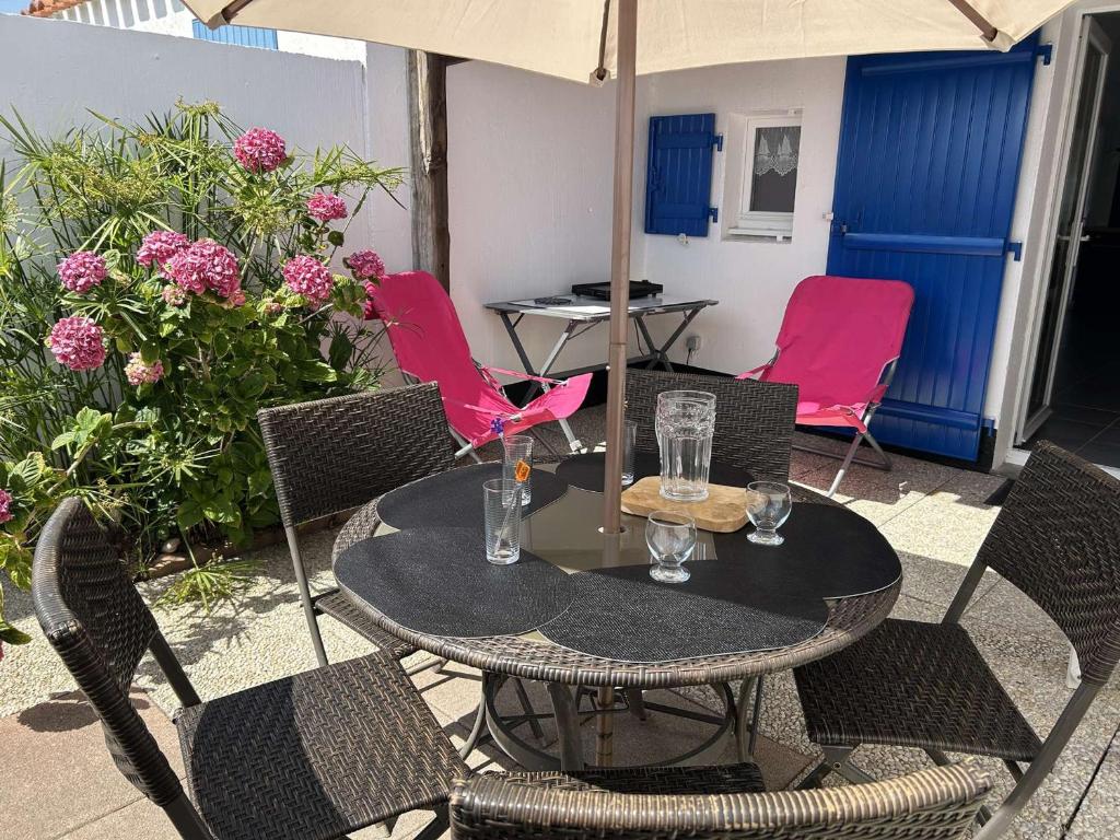 - une terrasse avec une table, des chaises et des fleurs dans l'établissement Maison rénovée 2 chambres, près mer, séjour TV - FR-1-224A-79, à Bretignolles-sur-Mer