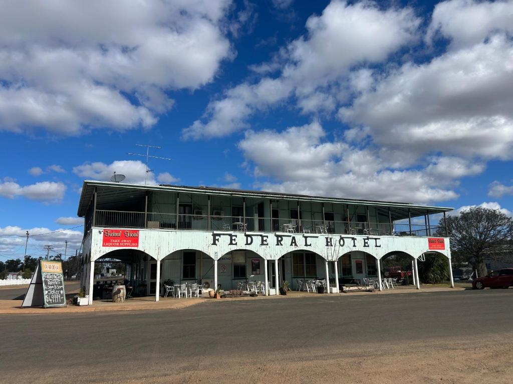 Un edificio blanco con una casa abandonada en la calle. en Federal hotel Wallumbilla, en Wallumbilla