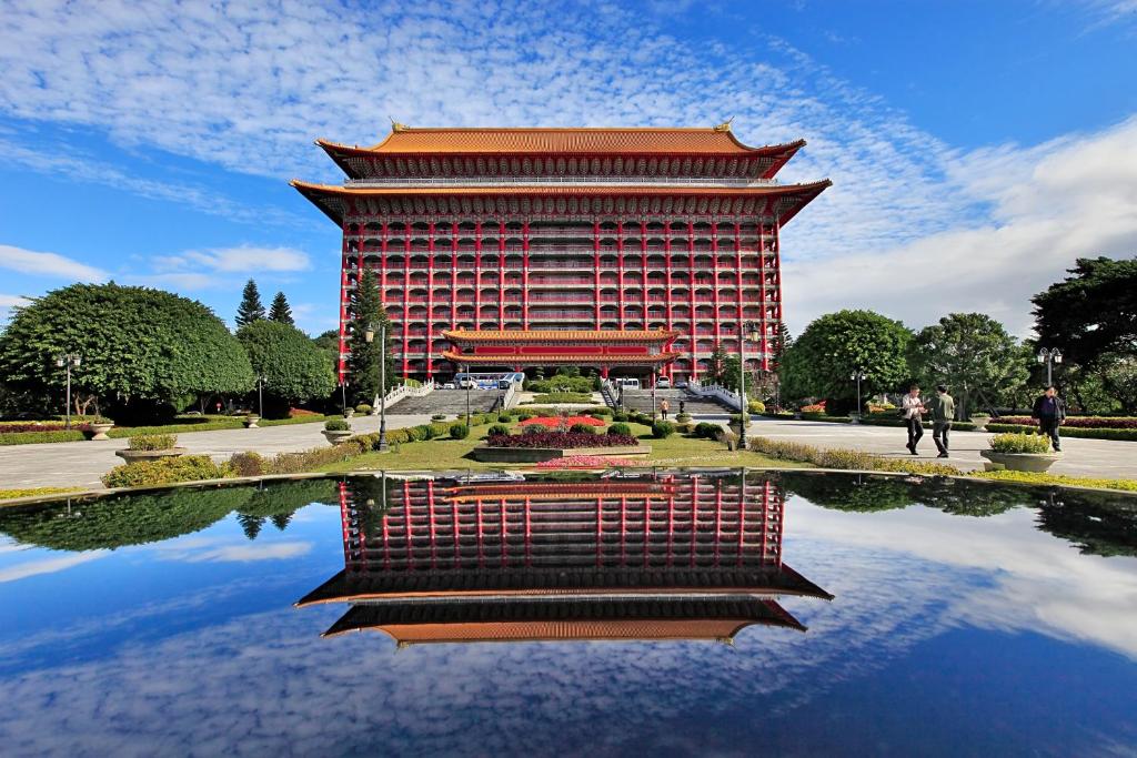 a building with a reflection in a pond in front of it at The Grand Hotel in Taipei