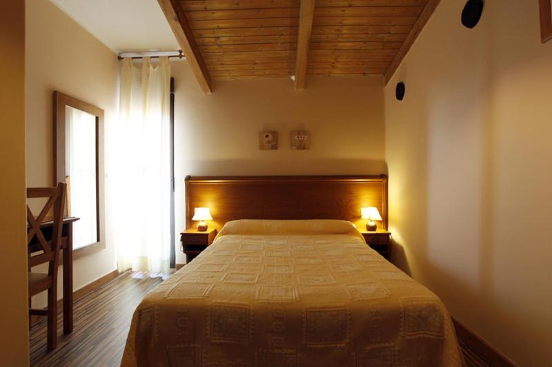 a bedroom with a bed and a window with two lamps at Apartamentos Hervasypunto in Hervás